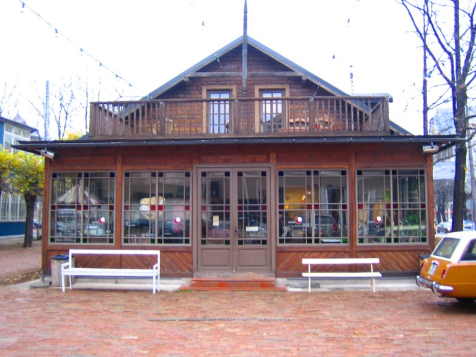 Grande baie avec vitraux surmontée d'une terrasse pour cette maison en bois de Riga. 